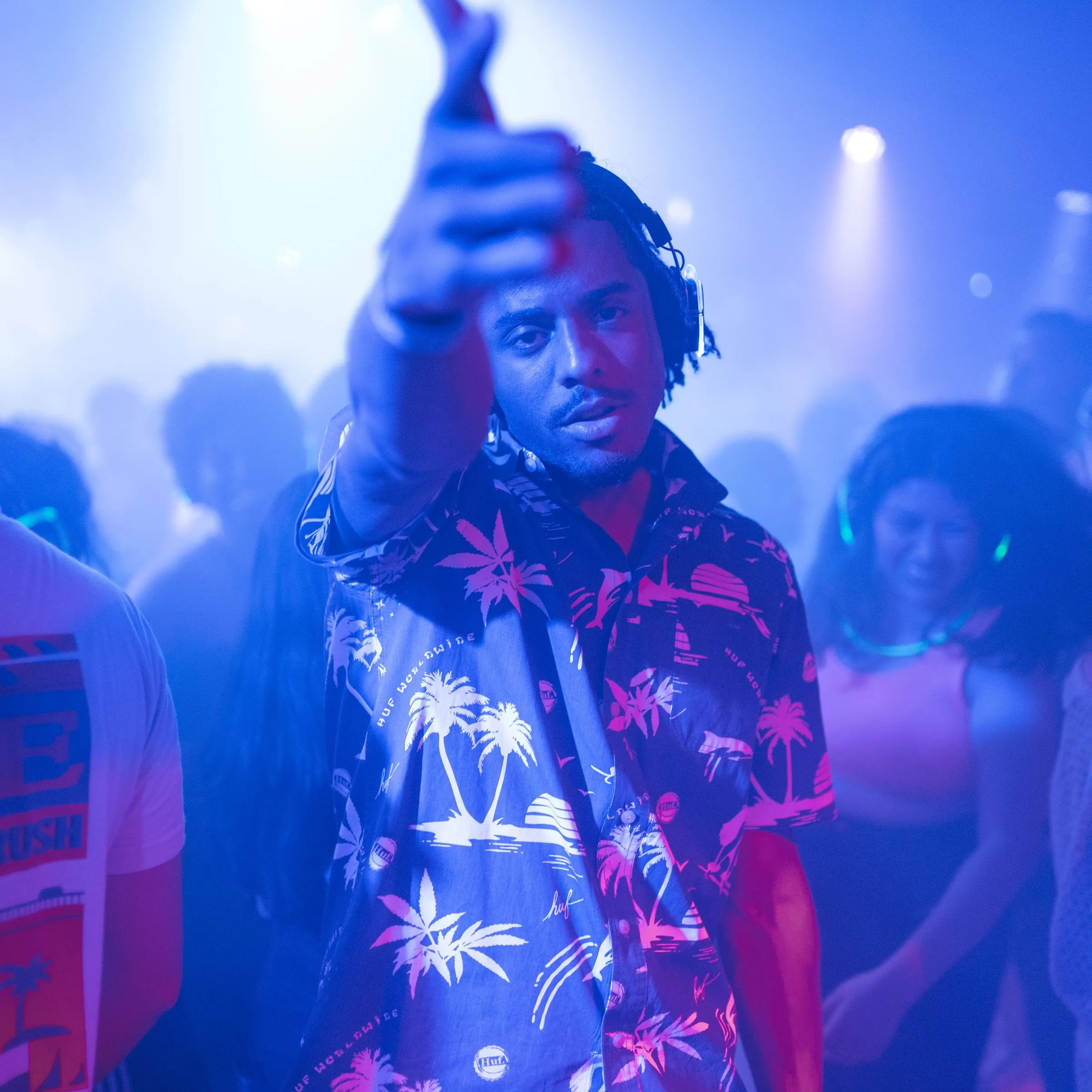 DJ with headphones performing under blue club lighting