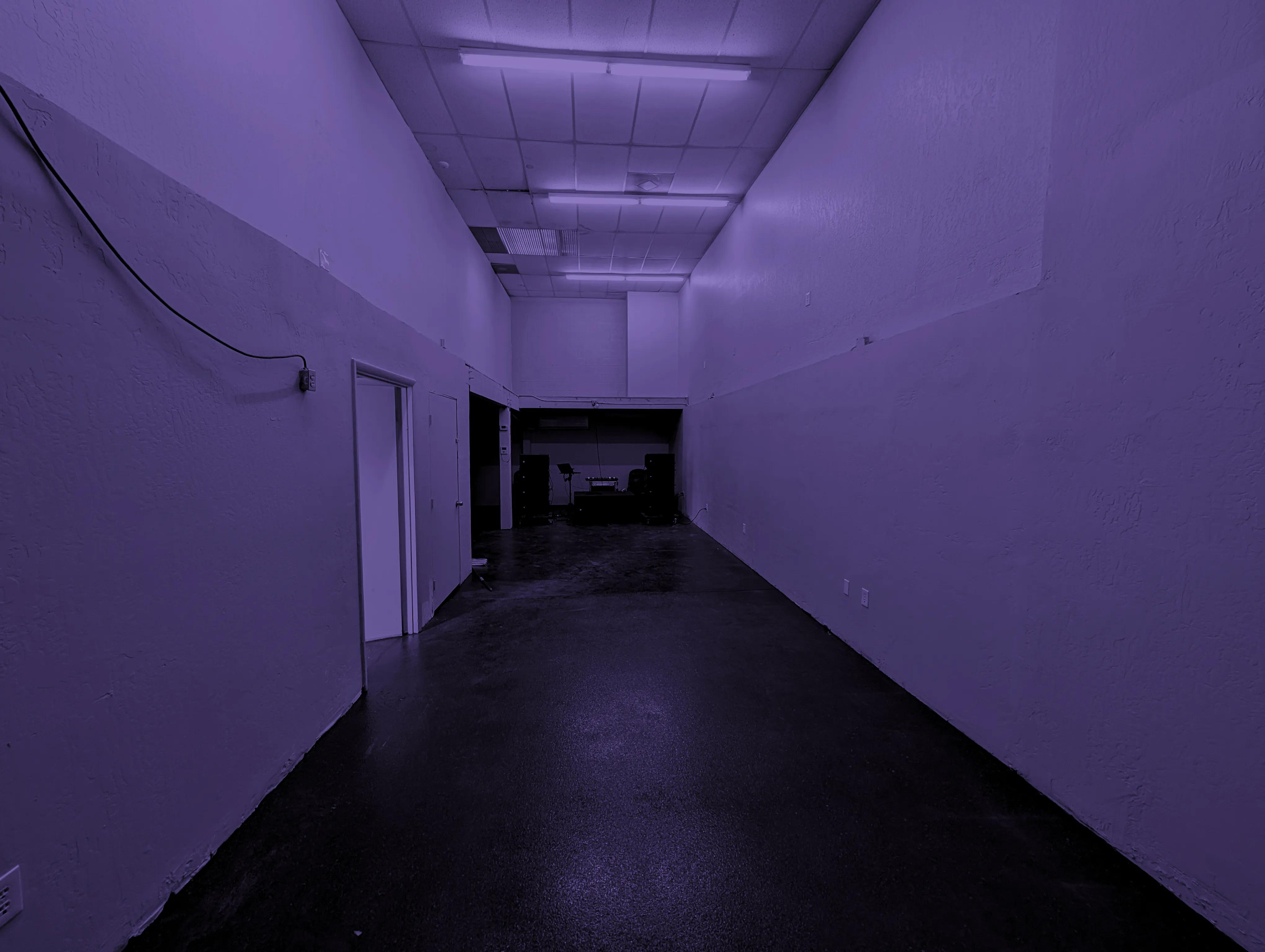 SoundTunnel venue hall with DJ booth and speakers under stage-graded lighting