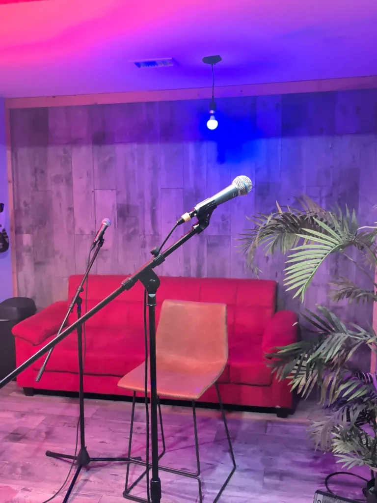 Studio A vocal booth view with microphones, red sofa, and neon lighting