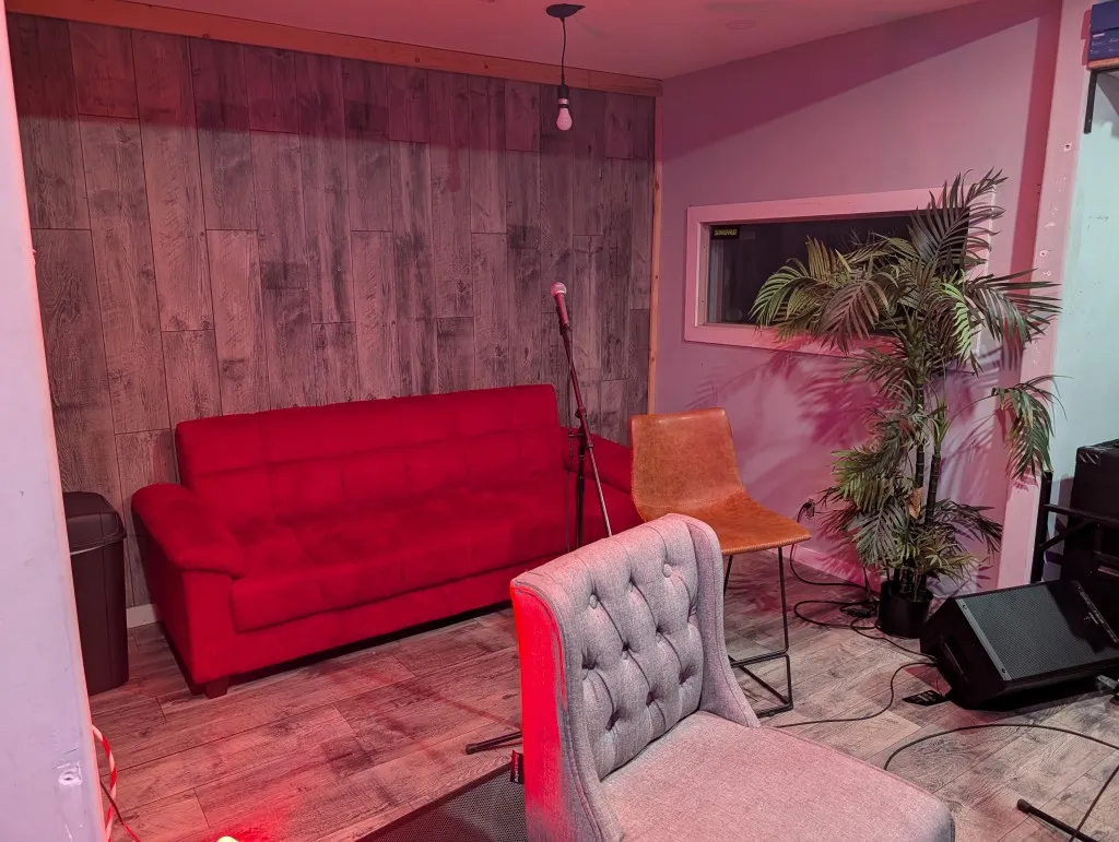 Studio A lounge corner with red sofa, mic stand, and pink lighting